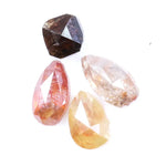 Collection of natural fancy color diamonds including pink, yellow, champagne and cognac loose diamonds with faceted cuts displayed on white background for fine jewelry and gemstone collecting.
