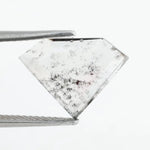 Shield cut lab grown diamond with clear body and natural-looking black inclusions in a salt and pepper pattern, faceted loose gemstone for custom jewelry