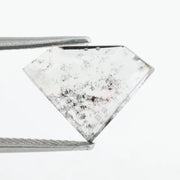 Shield cut lab grown diamond with clear body and natural-looking black inclusions in a salt and pepper pattern, faceted loose gemstone for custom jewelry