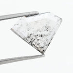 Shield cut lab grown diamond with clear body and natural-looking black inclusions in a salt and pepper pattern, faceted loose gemstone for custom jewelry