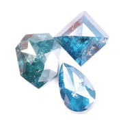 Collection of natural blue diamonds in unique geometric cuts including triangular, hexagon, and pear shapes with vivid ocean-blue tones and natural inclusions on a white background.