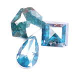 Collection of natural blue diamonds in unique geometric cuts including triangular, hexagon, and pear shapes with vivid ocean-blue tones and natural inclusions on a white background.
