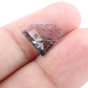 Shield cut lab grown diamond with clear body and natural-looking black inclusions in a salt and pepper pattern, faceted loose gemstone for custom jewelry