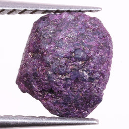 Purple rough diamond held between tweezers on a white background