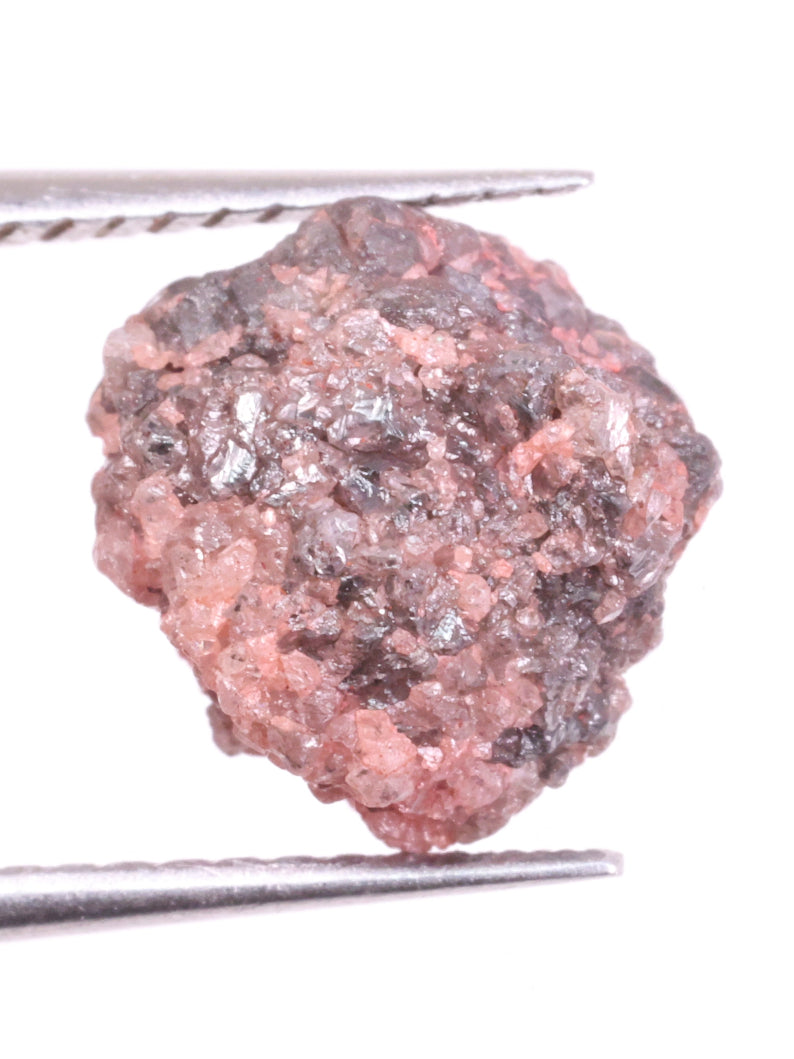 Raw light pink diamond held between tweezers on a white background