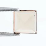 Square pyramid cut lab grown diamond with soft champagne tone, high clarity, polished facets, and modern geometric shape on a clean white background