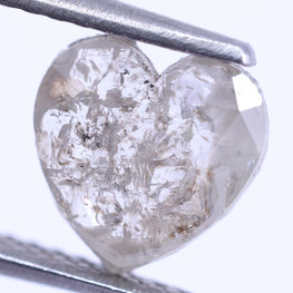 Heart-shaped diamond held by tweezers on a white background