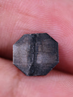 Octagon diamond held between fingers against a white background