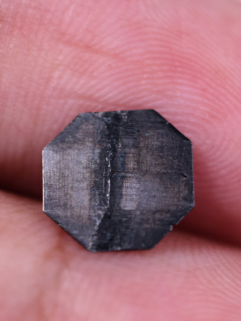 Octagon diamond held between fingers against a white background