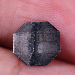 Octagon diamond held between fingers against a white background