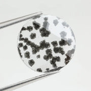 Round faceted lab grown diamond with distinctive black inclusions creating a salt and pepper effect inside a clear polished gemstone