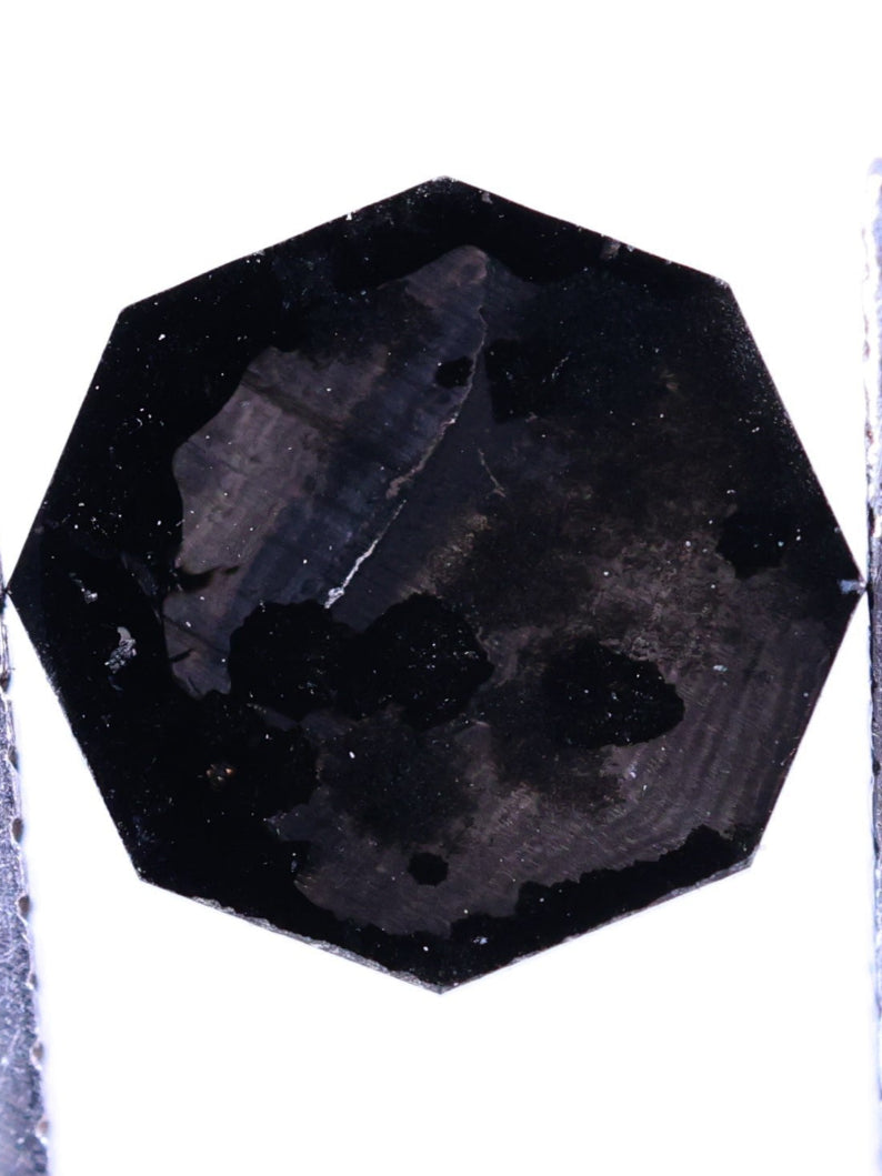 Black faceted lab grown diamond  on a white background