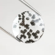 Round faceted lab grown diamond with distinctive black inclusions creating a salt and pepper effect inside a clear polished gemstone