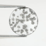 Round faceted lab grown diamond with distinctive black inclusions creating a salt and pepper effect inside a clear polished gemstone