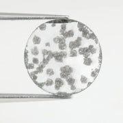 Round faceted lab grown diamond with distinctive black inclusions creating a salt and pepper effect inside a clear polished gemstone