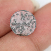 Round faceted lab grown diamond with distinctive black inclusions creating a salt and pepper effect inside a clear polished gemstone