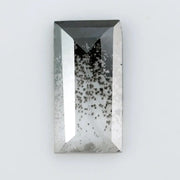 Baguette cut lab grown diamond with salt and pepper inclusions, showcasing a unique speckled galaxy pattern inside a clear faceted rectangular stone on a white background