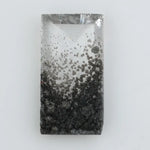 Baguette cut lab grown diamond with salt and pepper inclusions, showcasing a unique speckled galaxy pattern inside a clear faceted rectangular stone on a white background