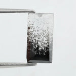 Baguette cut lab grown diamond with salt and pepper inclusions, showcasing a unique speckled galaxy pattern inside a clear faceted rectangular stone on a white background