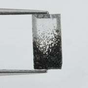 Baguette cut lab grown diamond with salt and pepper inclusions, showcasing a unique speckled galaxy pattern inside a clear faceted rectangular stone on a white background
