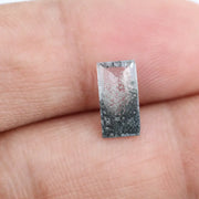 Baguette cut lab grown diamond with salt and pepper inclusions, showcasing a unique speckled galaxy pattern inside a clear faceted rectangular stone on a white background