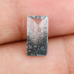 Baguette cut lab grown diamond with salt and pepper inclusions, showcasing a unique speckled galaxy pattern inside a clear faceted rectangular stone on a white background