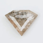 Close-up of a faceted lab grown diamond with visible natural-style inclusions, brilliant cut geometry, and soft champagne hue on a clean white background