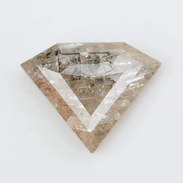 Close-up of a faceted lab grown diamond with visible natural-style inclusions, brilliant cut geometry, and soft champagne hue on a clean white background