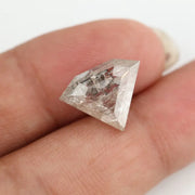 Close-up of a faceted lab grown diamond with visible natural-style inclusions, brilliant cut geometry, and soft champagne hue on a clean white background
