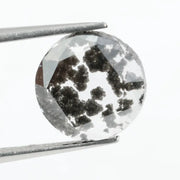 Round cut lab grown salt and pepper diamond featuring bold black dendritic inclusions in a transparent stone, faceted for brilliance and showcasing a unique natural pattern