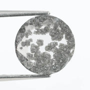 Round cut lab grown salt and pepper diamond featuring bold black dendritic inclusions in a transparent stone, faceted for brilliance and showcasing a unique natural pattern