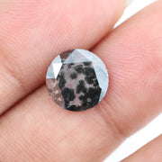 Round cut lab grown salt and pepper diamond featuring bold black dendritic inclusions in a transparent stone, faceted for brilliance and showcasing a unique natural pattern