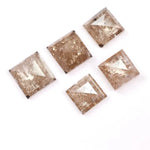 Five square step cut champagne lab grown diamonds with galaxy salt and pepper inclusions, pyramid faceting, and rustic brown tones displayed on a white background.