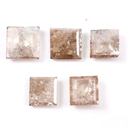 Five square step cut champagne lab grown diamonds with galaxy salt and pepper inclusions, pyramid faceting, and rustic brown tones displayed on a white background.