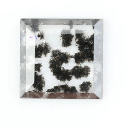 Clear lab-grown diamond with striking black natural-style inclusions inside a polished rectangular crystal, showcasing a unique modern gemstone aesthetic