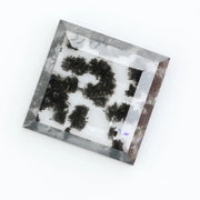 Clear lab-grown diamond with striking black natural-style inclusions inside a polished rectangular crystal, showcasing a unique modern gemstone aesthetic