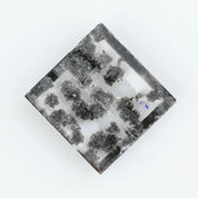 Clear lab-grown diamond with striking black natural-style inclusions inside a polished rectangular crystal, showcasing a unique modern gemstone aesthetic