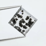 Clear lab-grown diamond with striking black natural-style inclusions inside a polished rectangular crystal, showcasing a unique modern gemstone aesthetic
