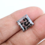 Clear lab-grown diamond with striking black natural-style inclusions inside a polished rectangular crystal, showcasing a unique modern gemstone aesthetic