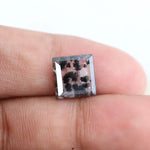 Clear lab-grown diamond with striking black natural-style inclusions inside a polished rectangular crystal, showcasing a unique modern gemstone aesthetic