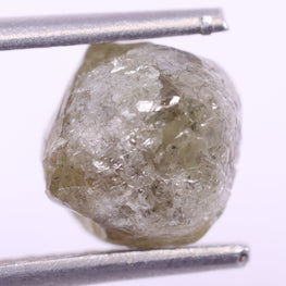 Raw diamond held between tweezers on a white background