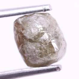 Raw diamond held between tweezers on a white background