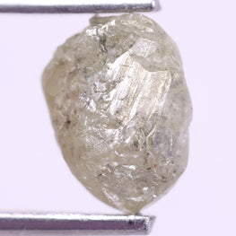 Raw diamond held between tweezers on a light purple background