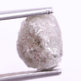Raw diamond held by tweezers on a white background