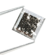 Sqaure step cut salt and pepper lab grown diamond with galaxy-like black and white inclusions, featuring a geometric faceted shape and transparent edges, ideal for unique engagement rings or custom jewelry designs