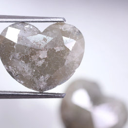 Heart-shaped diamond held by tweezers on a light background