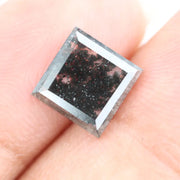 Sqaure step cut salt and pepper lab grown diamond with galaxy-like black and white inclusions, featuring a geometric faceted shape and transparent edges, ideal for unique engagement rings or custom jewelry designs