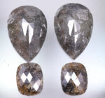 Four pear-shaped and cushion-shaped diamonds on a light gray background
