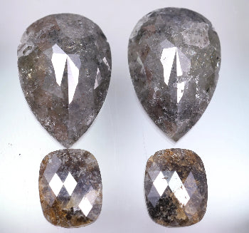 Four pear-shaped and cushion-shaped diamonds on a light gray background