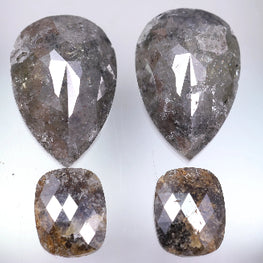 Four pear-shaped and cushion-shaped diamonds on a light gray background